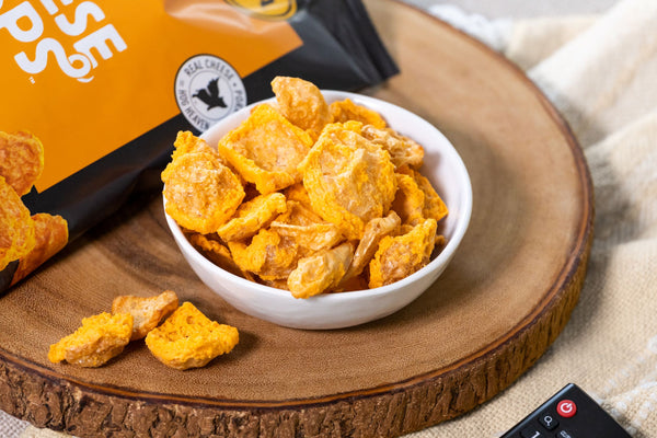 Cheddar Pork Rind Cheese Crisps displayed on a bowl on a slice of wood