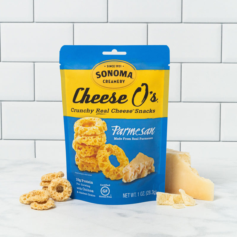 a bag of our Parmesan Cheese Os displayed in front of a white tile background with the ingredients arranged at the base
