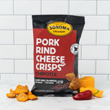 a bag of our chipotle pork rind cheese crisps displayed in front of a white tile background with the ingredients arranged at the base